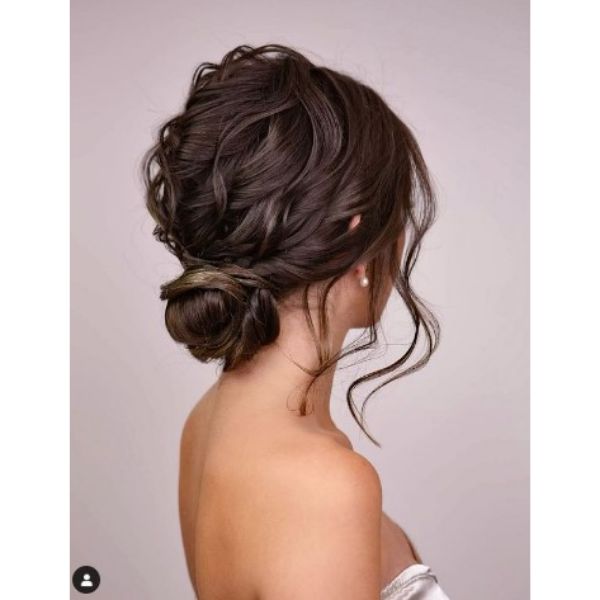 Dark Wavy Textured Wedding Updo With Falling Strands And Side Bun
