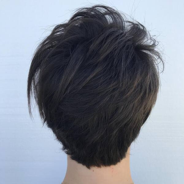 Dark Feathered Pixie Cut - A woman facing white wall