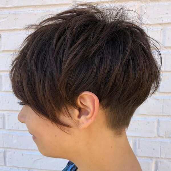 Short Back Shag with Inverted Bob in Front - A woman with a concrete brick white wall