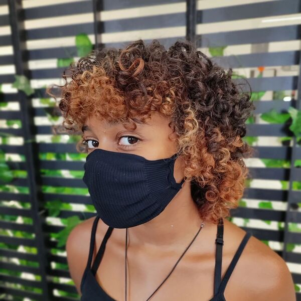 Curly Mullet With Almond Highlights - a woman wearing a black face mask