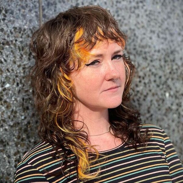 Curly Mullet With Orange Under Lights - a woman wearing a striped shirt