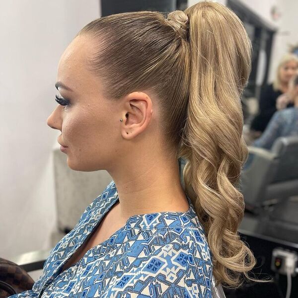 Easy High Ponytail Updo with Sleek Curls - A woman wearing a blue printed blouse