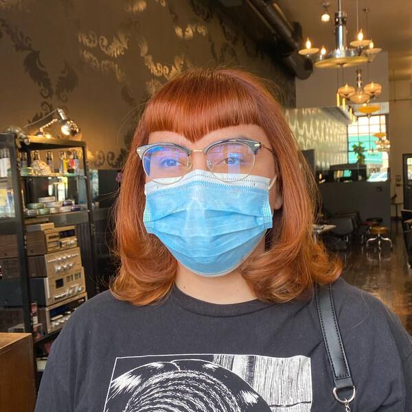 V-Shaped Bangs with Copper Tint Wavy Hair- a woman wearing a face mask