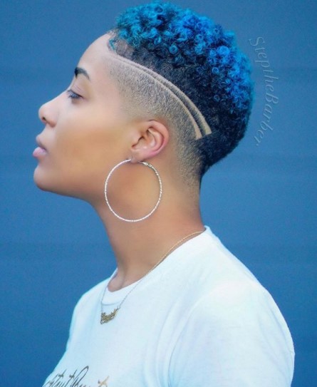 a woman with High Fade with Blue Curly Top shaved hairstyles for black women with huge earrings