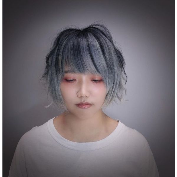 A girl with make up with her modern asymmetric bob with ash grey highlights hairstyle