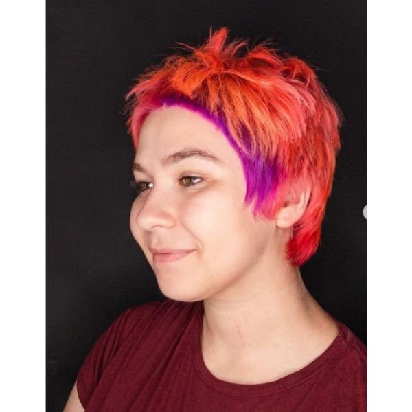 A girl smiling with her super short orange with purple highlights hairstyle