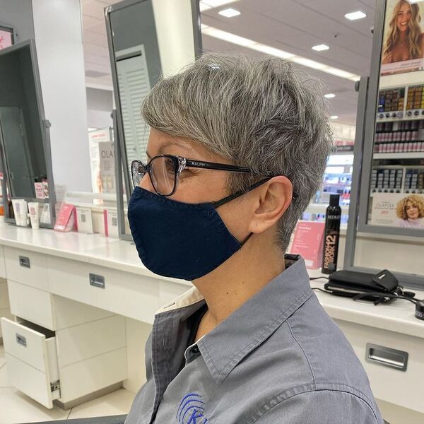 Gray Layered Pixie with Short Bangs - A woman inside a salon, wearing a blue mask