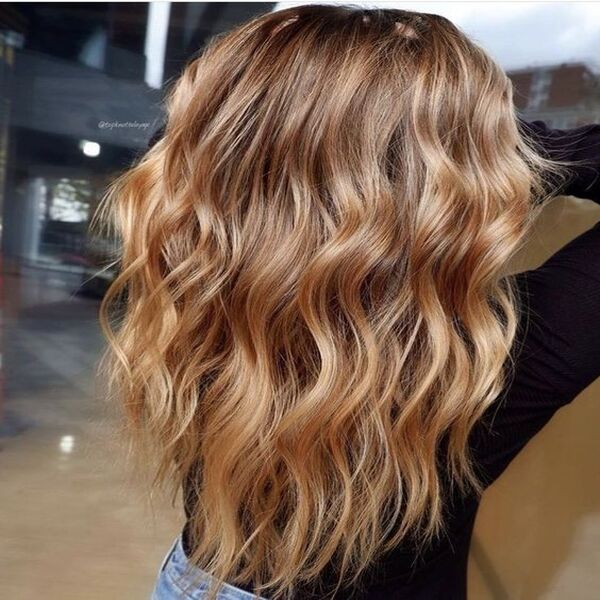 Shiny Caramel Balayage Highlights - A woman in her black top and denim pants