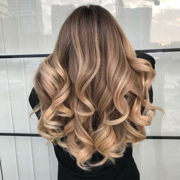 Curly Hair with Shiny Caramel Balayage - A women wearing a black sweater