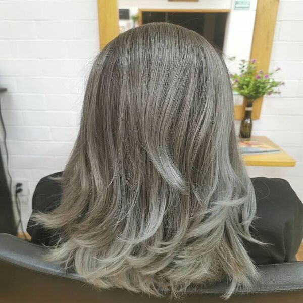 Long Hair Grey Ash Blonde with Curly Tips Hair - A woman sitting on the chair
