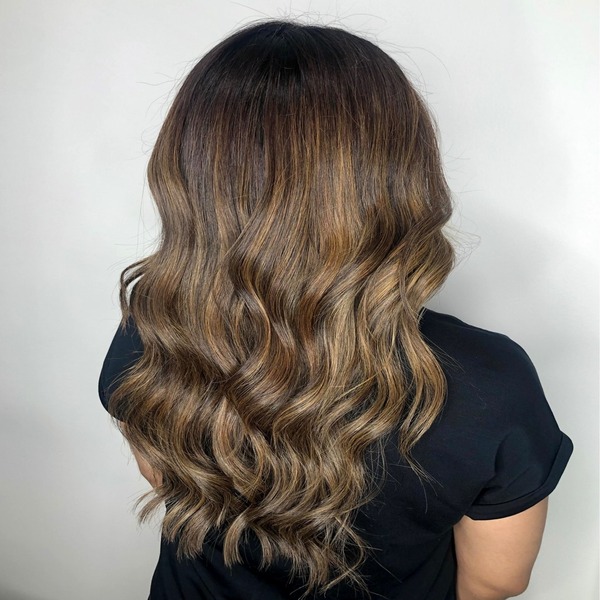 Caramel Toffee Balayage for Long Hair - A woman facing the white painted wall