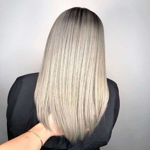 Outstanding Ash Silver Blonde for Long Length Hair - A woman wearing a black salon cape