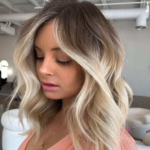 Airy Platinum Blonde Balayage - a pretty young woman wearing a peach top