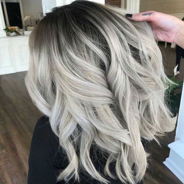 Black Hair with Platinum and White Balayage - a woman with black nails holding the hair of another woman