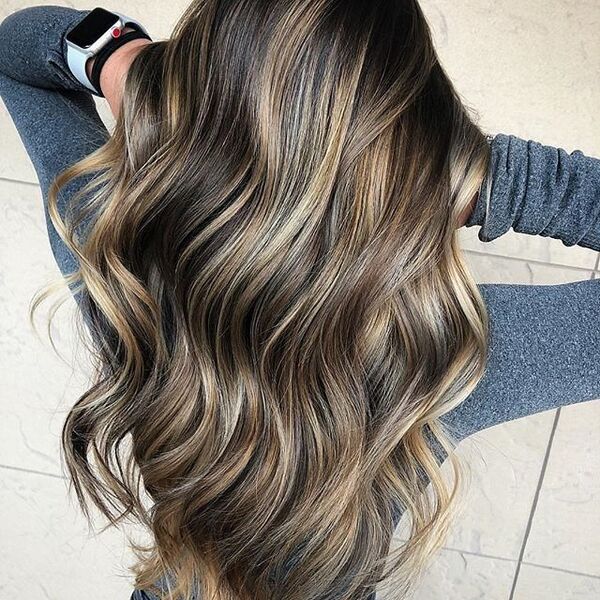 Blonde Highlights for Brown Hair - a woman holding her hair and is wearing a fitted gray long sleeve
