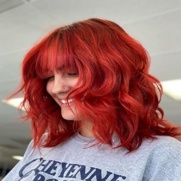 Bright Red Wolf Haircut Curly Hair - a red head woman wearing a gray shirt and a smile on her face