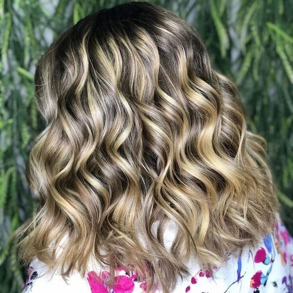 Caramel Blonde Highlights on Curly Hair - a woman wearing a floral blouse