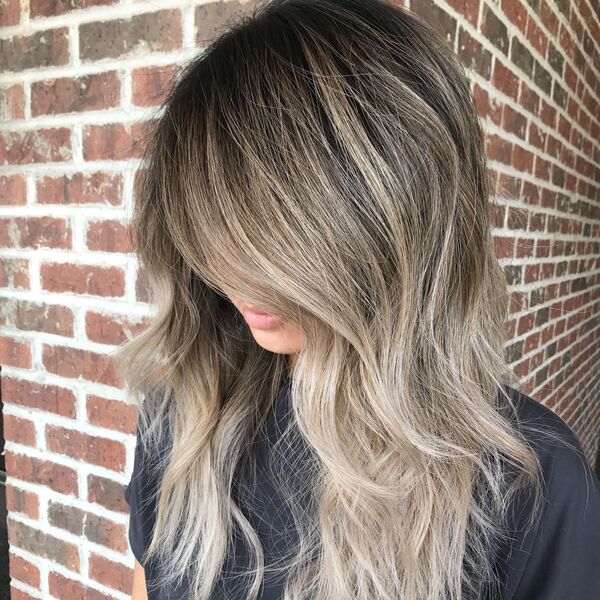 Medium-Length High-Contrast Balayage - a woman standing in a brick wall