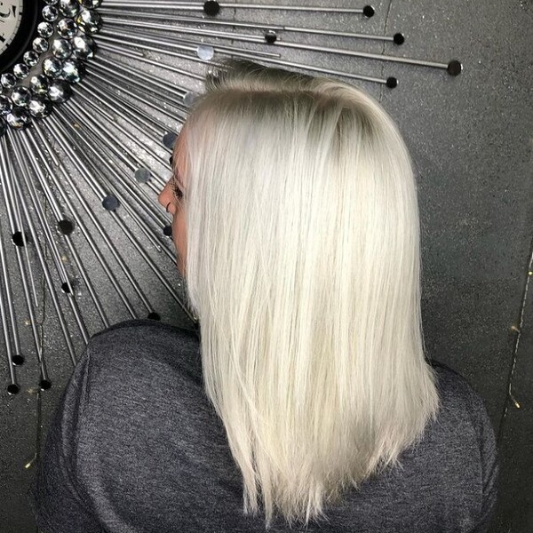 Platinum Bleach Blonde Hairstyle - a woman wearing a gray shirt and has a piercing on her nose