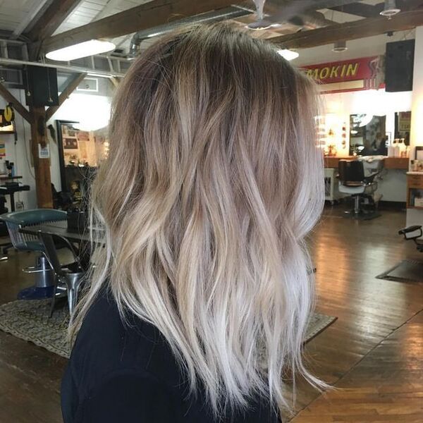 Root Stretch Ash Blonde - a woman wearing a black shirt and is in a salon