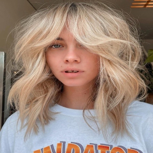 Shaggy & Voluminous Wolf Cut Hair - a young girl with space in her teeth is wearing a white shirt