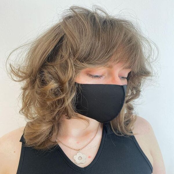 Short and Voluminous Wolf Hair - a woman wearing a flower pendant necklace and is wearing a black facemask