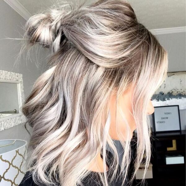 A girl in her room and set her hair into a half ponytail with blonde balayage hair