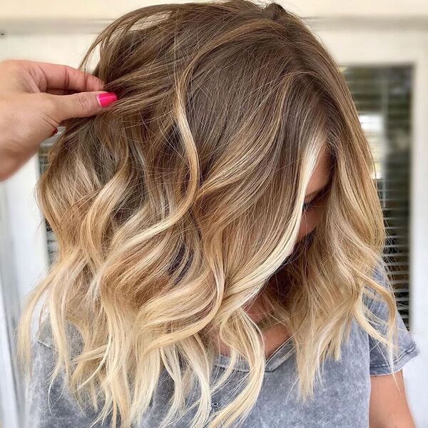Soft Blonde Balayage on a Lob - a woman wearing a gray shirt and someone is holding her hair