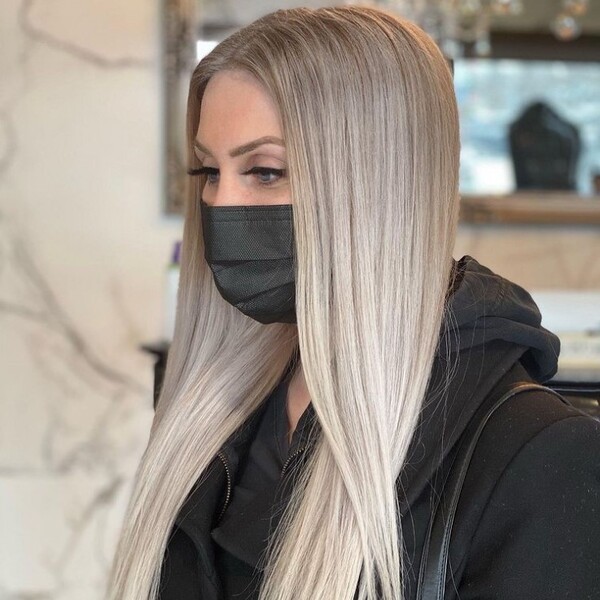 blonde hair with platinum highlights - a woman wearing a black hood jacket and a facemask