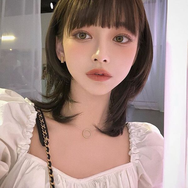 edgy korean mullet wolf haircut - a girl wearing a puff sleeve blouse and a necklace with a round pendant