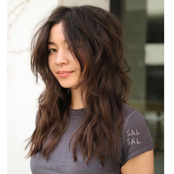 long wolf haircut - a girl with a mole below her nose is wearing a gray fitted shirt