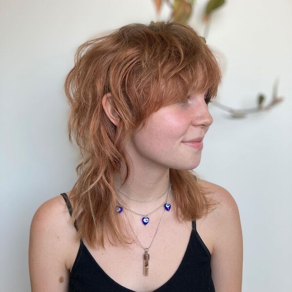 medium length wolf with fringe - a young woman smiling and wearing a spaghetti strap blouse