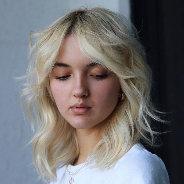 wolf cut with wispy end - a woman wearing a white shirt looking down