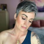 50 Short Haircuts for Older Women in 2022 - a woman with tattoos and is wearing gold jewelries
