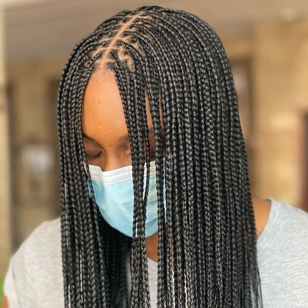 A woman on color gray shirt with her face mask on with cornrow braids