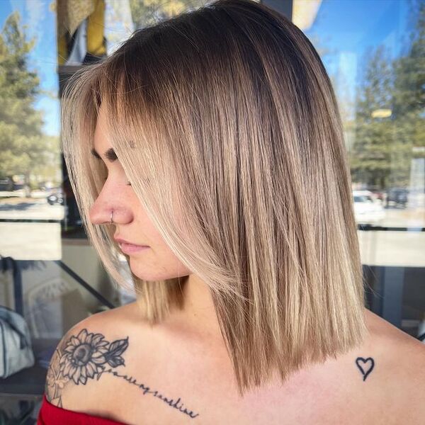 Blonde Short Hair Curtain Bangs with Dark Roots - A woman with tattoos
