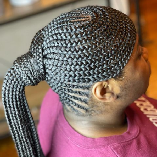 A woman sitting with her braided swoop hairstyle