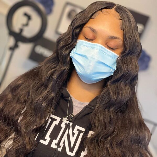 Center Weave Hairstyle - A woman with blue surgical face mask wearing a black printed jacket