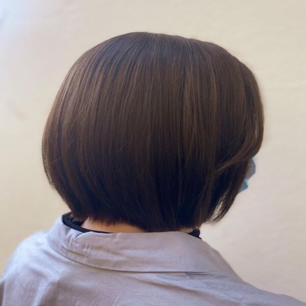 A woman sitting with her dark brown black with brown highlights bob hair