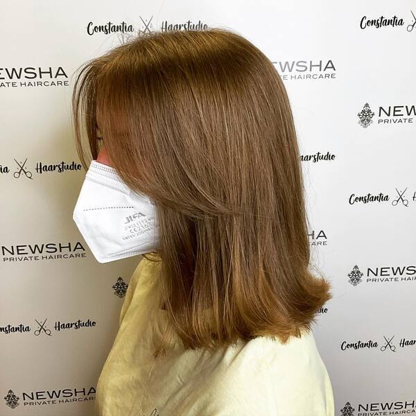 Dark Brown Curtain Bangs with Flip Tips - A woman wearing a white mask