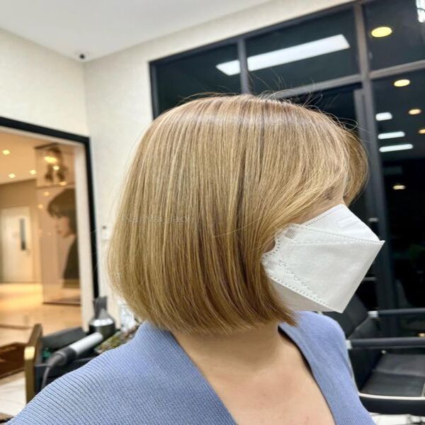 Light Copper Brown Highlights Curtain Bangs - A woman wearing a white mask