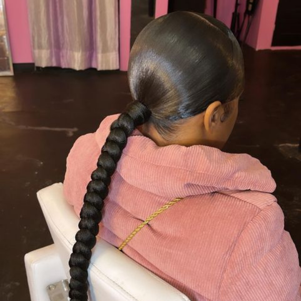 Long Braided Swoop Pony Hair - A woman wearing a pink jacket
