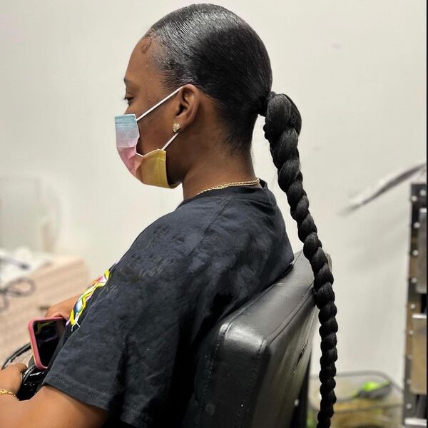 Low Sleek Braided Ponytail - A woman with colorful face mask wearing a black printed shirt