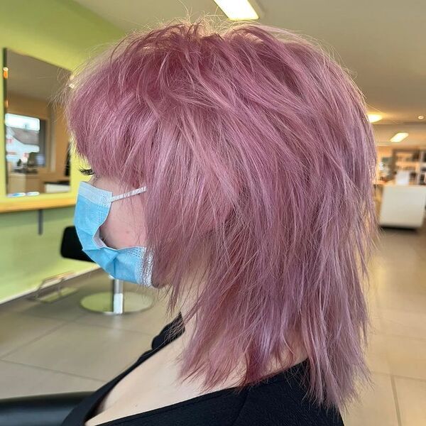 A woman sitting with her purple blonde wolf cut hair
