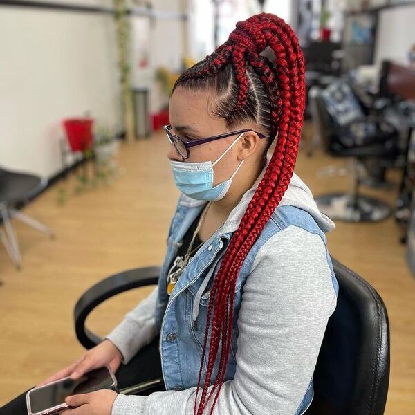 Red Hair Knotless Ponytail Braids - A woman with eyeglasses wearing a denim jacket and a blue surgical face mask