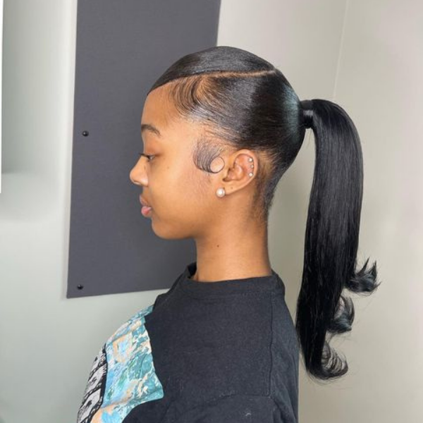 A woman standing with her sleek edges bun hairstyle 