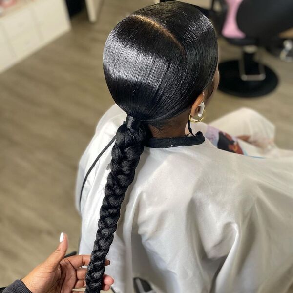Smooth and Sleek Braided Ponytail - A woman wearing a beauty salon white cape