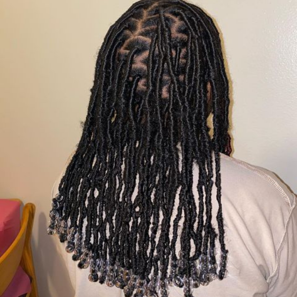 Soft Locs with Beads Hair - A woman facing the white wall