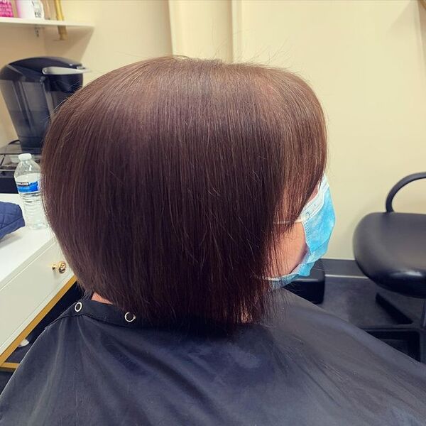 Warm Chesnutt Brown Hair - A woman wearing a black salon cape