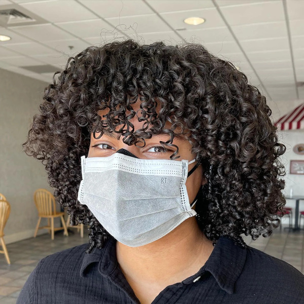 Afro Bouncy Curls With Bangs - a woman wearing a face mask